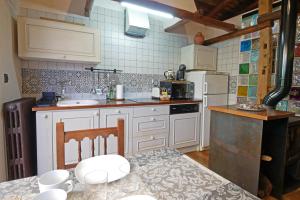 a kitchen with white appliances and a table and chairs at Casa Rural El Cuco in Robledillo