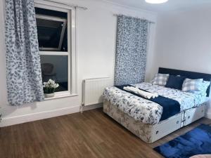 a bedroom with a bed with blue curtains and a window at Stylish & Cosy 3 BR in Gravesend in Northfleet