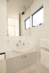 ein weißes Badezimmer mit Waschbecken und Spiegel in der Unterkunft Cozy and Comfortable in Central Christchurch with Hagley Park Views in Christchurch