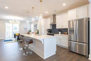 eine Küche mit weißen Schränken und einem Edelstahlkühlschrank in der Unterkunft Birdsong Bungalow - Hot Tub, Game Room, Fire Pit in Charlotte