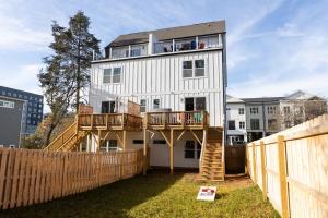 ein weißes Haus mit einer Terrasse und einem Zaun in der Unterkunft Birdsong Bungalow - Hot Tub, Game Room, Fire Pit in Charlotte