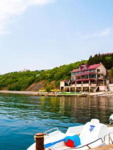 ein Boot im Wasser neben einem großen Haus in der Unterkunft Ai-Todor Hotel in Bondarenkovo