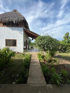 a house with a thatched roof and a sidewalk at Cabaña Anahuac in Chinandega