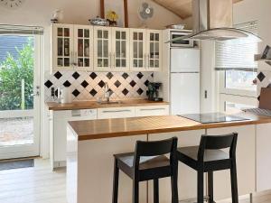 a kitchen with white cabinets and a counter with stools at 8 person holiday home in Rødby-By Traum in Rødby