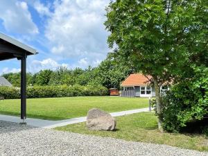 a rock next to a tree and a house at 6 person holiday home in Sydals-By Traum in Neder Lysabild