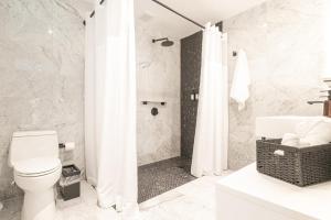 ein weißes Badezimmer mit Dusche und Toilette in der Unterkunft El Carlton - KingRoom Pool - Resort Vibe Near Beach in San Juan