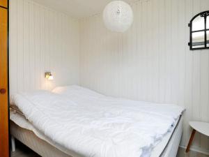 5 person holiday home in Vejers Strand-By Traum في فايرس ستراند: سرير أبيض كبير في غرفة بيضاء مع مصباح