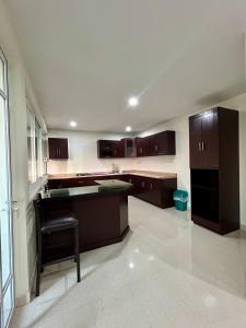 a large kitchen with brown cabinets and a chair in it at House near IMSS Trinidad Santa Cruz Tlaxcala in Santa María Atlihuetzián
