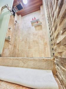 a bathroom with a shower with a stone wall at Casa Costa Rica in Jacó