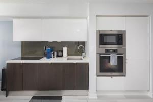 een keuken met witte kasten, een spoelbak en een magnetron bij Toronto Getaway 2BR Condo w City Views in Toronto