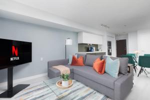 een woonkamer met een grijze bank en een tv bij Toronto Getaway 2BR Condo w City Views in Toronto
