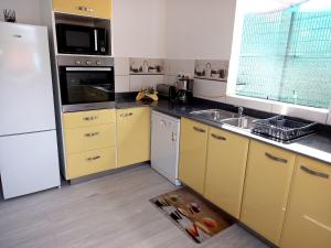 a kitchen with yellow cabinets and a white refrigerator at L ombre du manguier in Grand-Bourg +15 photos