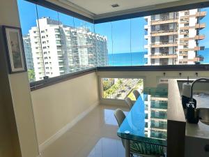 Un balcón con una mesa azul y algunas ventanas. en Apartamento Barra da Tijuca Frente Mar, en Río de Janeiro