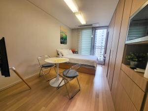 a small room with a bed and a table and chairs at #Long-term accommodation inquiries#Suwon Convention Center#Gwanggyo Lake Park#Daily bedding change in Suwon