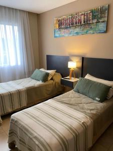 a hotel room with two beds and a window at Departamento Rincon Pinamar in Pinamar +11 photos