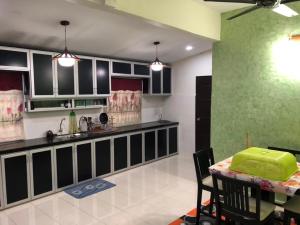 a kitchen with a table and a green wall at Caliph Homestay in Jitra
