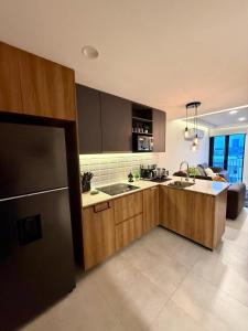 Una cocina con gabinetes de madera, un fregadero y un refrigerador. en Cielito Lindo Studio in the heart of Chapultepec, en Guadalajara