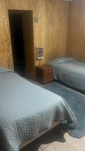 a bedroom with two beds and a dresser and a bed sidx sidx at Pensión Hospital in Maipo