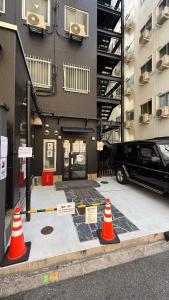 twee oranje verkeerskegels voor een gebouw bij 心斎橋難波関空直通 Ambers Hostel in Osaka