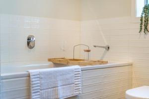 a white bathroom with a tub and a sink at Luxury Beachfront Apartment in Wellington +28 photos