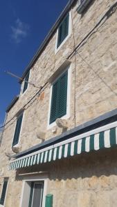 a stone building with green shutters on it at Buena Vis-ta Apartments with the Sea View in Vis