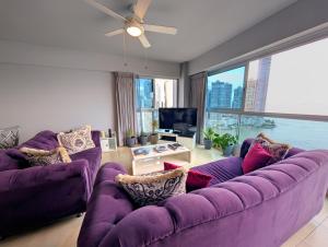 una sala de estar con sofás morados y una gran ventana. en YC 2307 l Av Balboa 2 BDR bay view, en Panamá