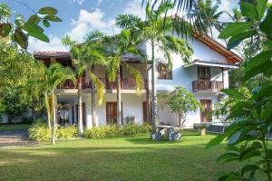 an exterior view of a house with palm trees at Hikka Resort in Hikkaduwa