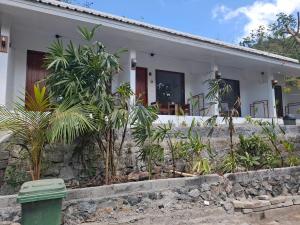 a white house with trees in front of it at Teman Homestay in Kuta Lombok