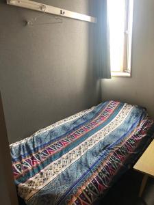 Una cama con una colcha encima en una habitación. en ゲストハウスブルーオーシャン那覇, en Naha