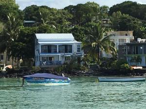 a boat in the water in front of a house at Kreolia Blue-Waters in Trou d'Eau Douce