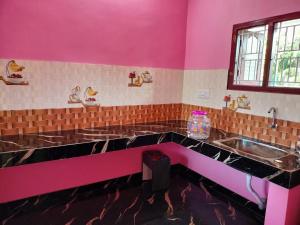 a pink kitchen with a sink and a counter top at Isakki Cottage in Thiruchendur