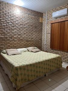 łóżko w pokoju z ceglaną ścianą w obiekcie Casa de Praia em Flecheiras Ana w mieście Trairi