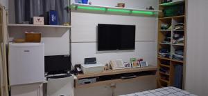 a living room with a tv and a shelf with a computer at Minha morada in Ananindeua