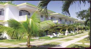 a large white building with palm trees in front of it at Fun Holiday Beach Hotel in Negril