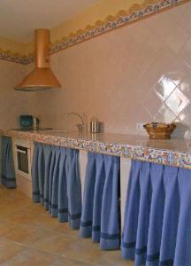 uma cozinha com cortinas azuis e uma bancada em Casa Rural Del Antiguo Hojalatero em Ibdes