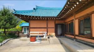 una casa con una panchina e un tetto blu di Yangyang 88 Hanok Stay a Yangyang