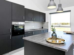 a kitchen with black cabinets and a large window at Modern Retreat with Spa - By Traum Ferienwohnungen in Løkken