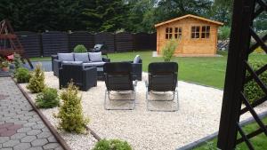 a patio with chairs and a couch and a dog house at Ostfriesisches Landhaus in Wittmund