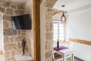 een kamer met een stenen muur met een tafel en een tv bij Sir George Luxury Suites in Split