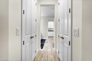 a hallway with white doors and wooden floors at Spacious Suite in modern house in Orlando