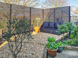 a patio with a blue couch and some plants at Lavender Cottage in Louth