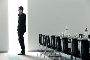 a man standing in front of a table with chairs at Troia Design Hotel in Troia