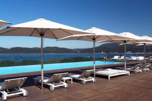 uma fila de cadeiras e guarda-sóis ao lado de uma piscina em Troia Design Hotel em Tróia