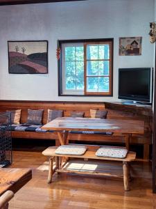 a living room with a wooden table and a tv at Ringo Lodge Hakuba in Hakuba