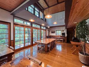 a large dining room with wooden tables and windows at Ringo Lodge Hakuba in Hakuba