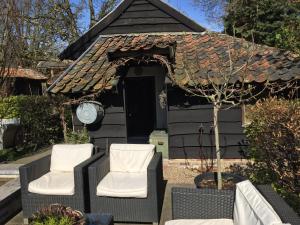 two chairs and a house with a roof at Onder de Noot in Baarlo