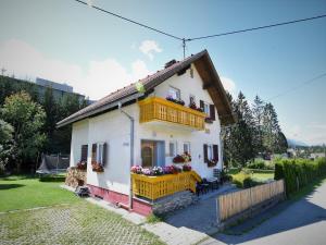 a small white house with a yellow balcony at Apartment in Tröpolach near Nassfeld in Tröpolach