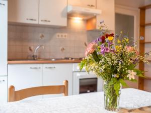 a vase of flowers sitting on a table in a kitchen at Apartment in Tröpolach near Nassfeld in Tröpolach +23 photos