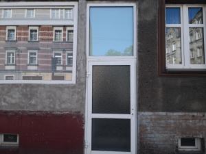 a door in the side of a building with two windows at Grottgera Inn Bytom in Bytom