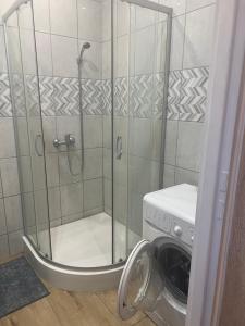 a shower stall in a bathroom with a washing machine at Grottgera Inn Bytom in Bytom